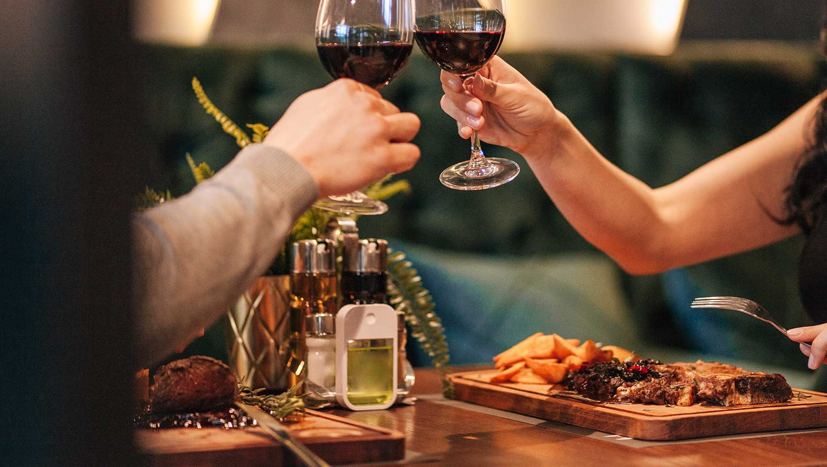 A couple at dinner cheersing red wine