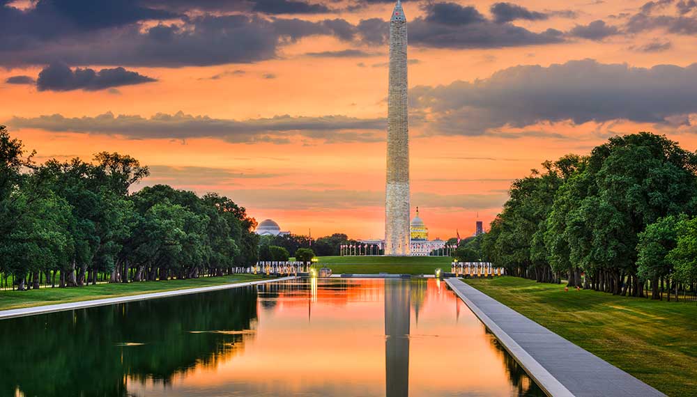 A warm sunset glows behind the Washington Monument and National Mall Reflecting Pool