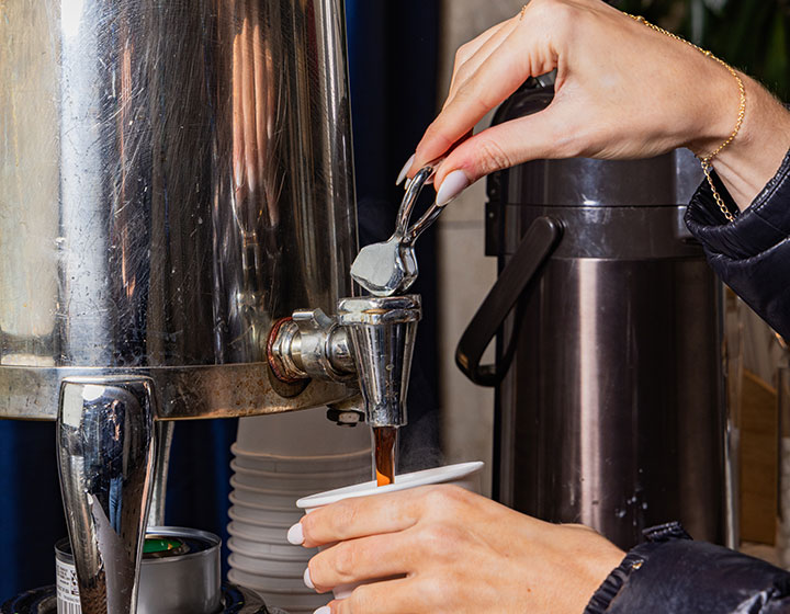 woman getting coffee from a coffee pot