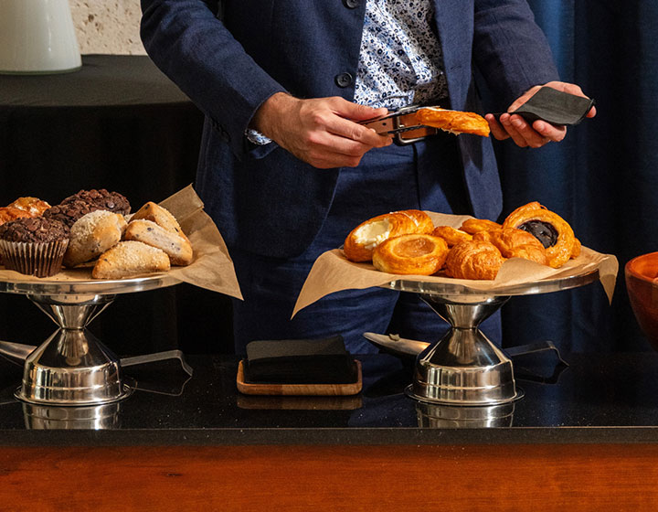 man taking some breakfast pastries from a table